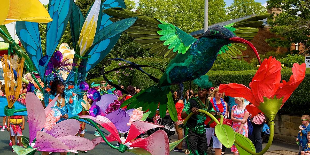 Caribbean Carnival Former Preston Caribbean Carnival parade with people dressed in extravagant bird costumes.