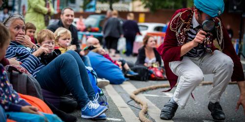 Families sat around a performance on Preston Flag Market, taking place during the annual Lancashire Encounter event.