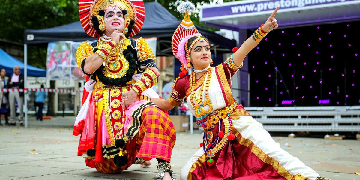 Main image: South Asian performance taking place. South Asian performance taking place during Mela 2021 on Preston Flag Market.