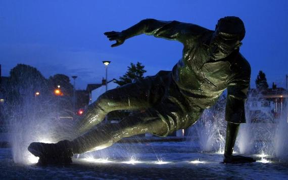 Sir Tom Finney "Splash" statue lit up at nighttime.