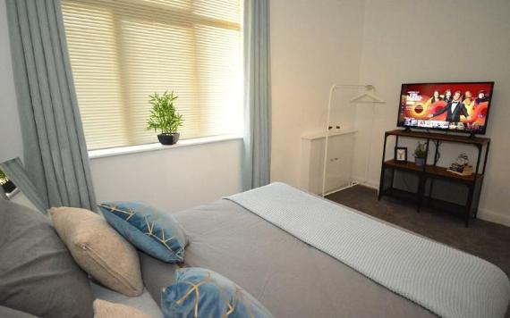 F.G. Aparthotel grey and blue modern bedroom with TV.