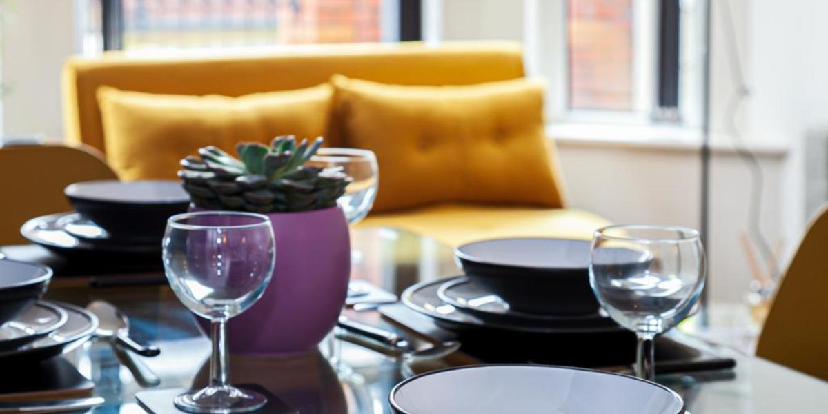Succulent plant and wine glasses on glass kitchen table with yellow sofa in background at Fulwood Heights apartment. Succulent plant and wine glasses on glass kitchen table with yellow sofa in background at Fulwood Heights apartment.