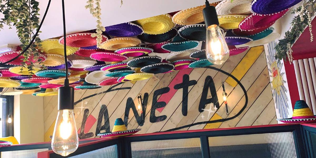 Main image: Colourful Mexican hats on ceiling inside La Neta Mexican restaurant. Colourful Mexican hats on ceiling inside La Neta Mexican restaurant.