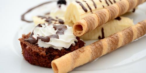Close up of chocolate and banana dessert with wafer straws on a white plate.