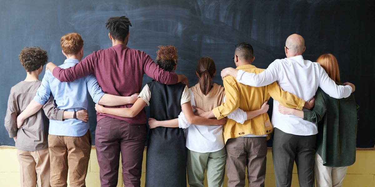 Main image Intact Centre Diverse group of people with arms around each other facing away from camera.