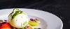 Poached egg dish on plate against black background.